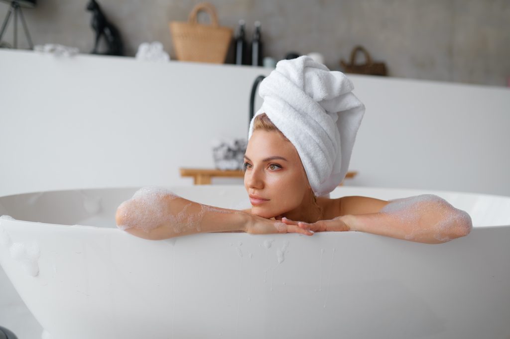 Portrait of gorgeous woman in towel on head taking bath